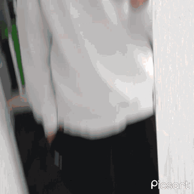 a person in a white shirt and black pants is standing in front of a white wall .