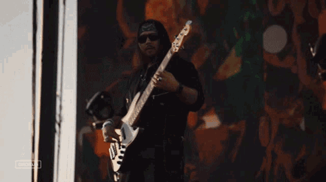 a man is playing a guitar in front of a large screen that says cacahua on it