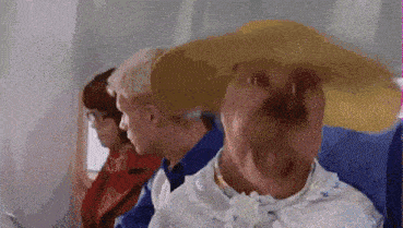 a woman wearing a straw hat is sitting on an airplane with other people .