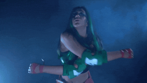 a woman with green hair and green elbow pads is dancing in a dark room .