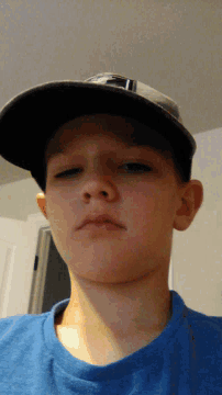 a young boy wearing a blue shirt and a baseball cap
