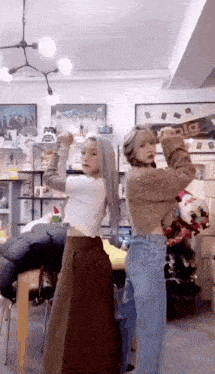 two girls are standing next to each other in a room with a christmas tree .