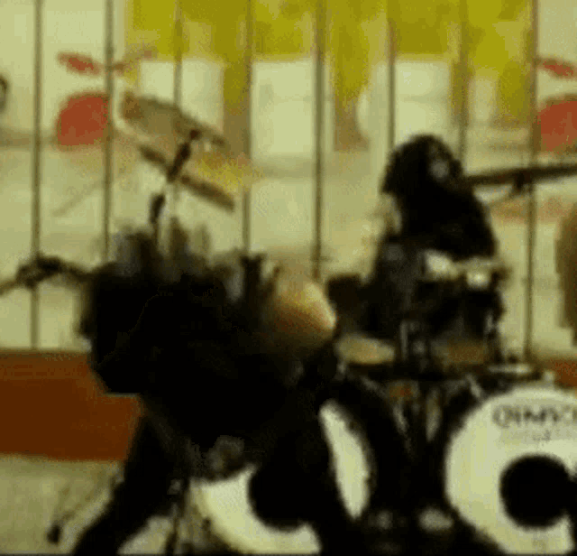 a man is playing drums in front of a sign that says ' cc ' on it