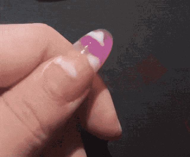 a close up of a person 's finger with a purple and white nail polish