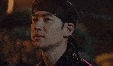 a close up of a man wearing a headband and a pink shirt