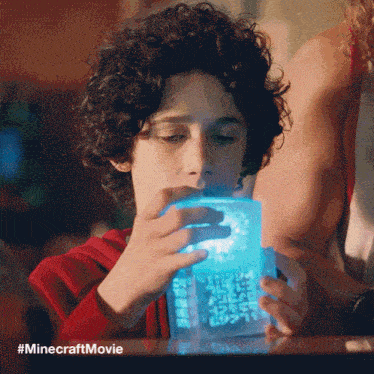 a young boy is looking at a minecraft movie item