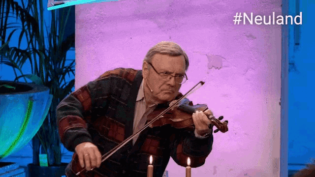 a man is playing a violin in front of candles and a sign that says #neuland