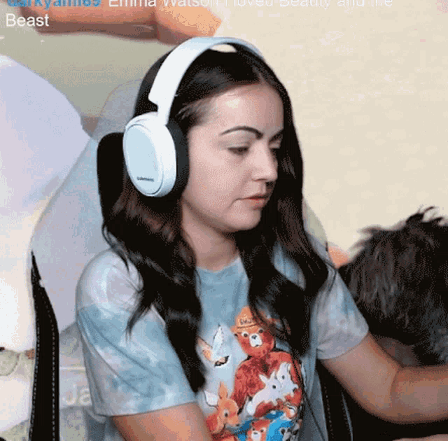 a woman wearing headphones and a tie dye shirt is sitting in a chair