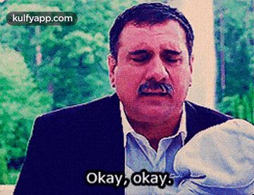a man with a mustache is holding a baby and saying okay okay okay