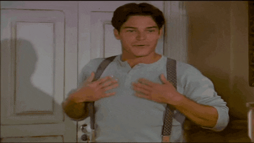 a man wearing suspenders and a blue shirt is holding his stomach