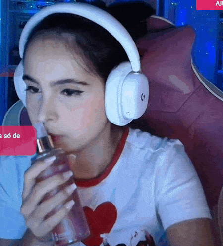 a girl wearing headphones drinks from a bottle
