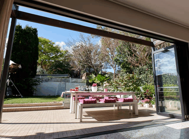 a patio with a table and benches and flowers on it