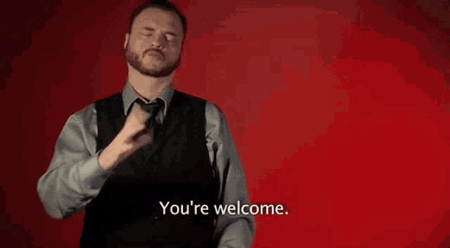 a man in a suit and tie says " you 're welcome " in front of a red background