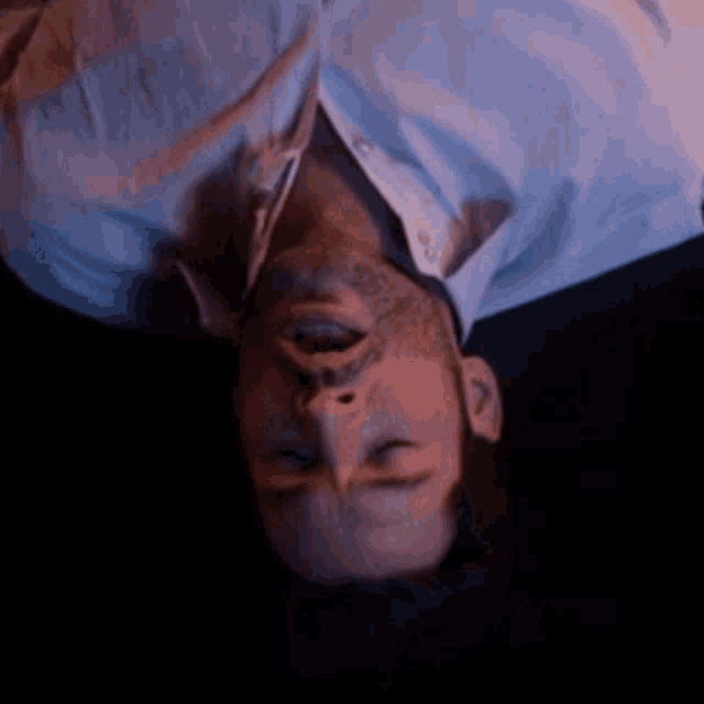 a man in a white shirt is laying upside down with his mouth open