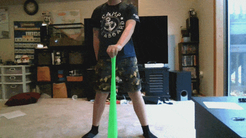 a man wearing a black shirt that says camp aboard is holding a green bat