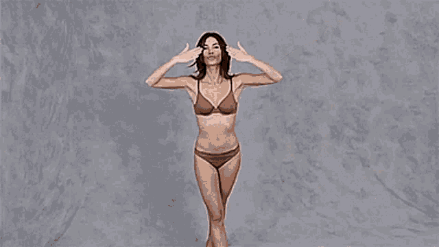 a woman in a brown bikini is standing with her arms outstretched