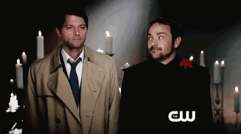 two men are standing next to each other with candles in the background and a cw logo in the foreground