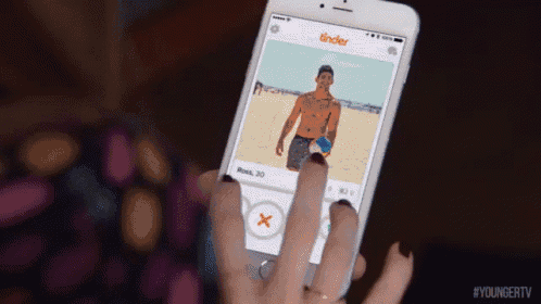 a woman is holding a cell phone with tinder on the screen