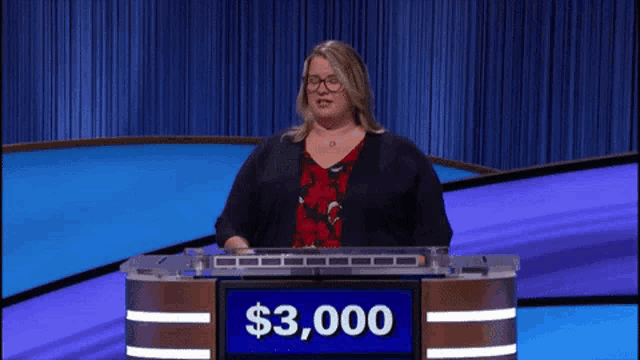 a woman stands behind a podium with a $ 3,000 sign on it
