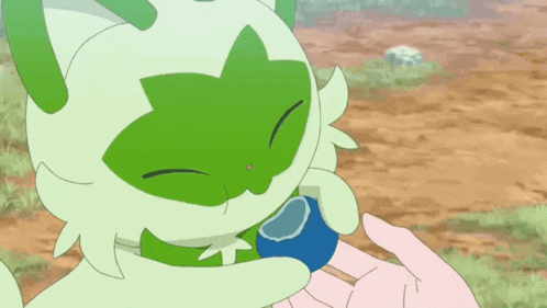 a green and white cartoon animal is being held by a person 's hand