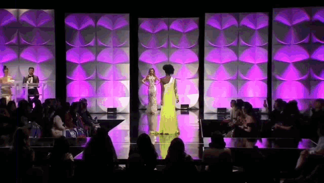 two women are walking down a runway at a fashion show