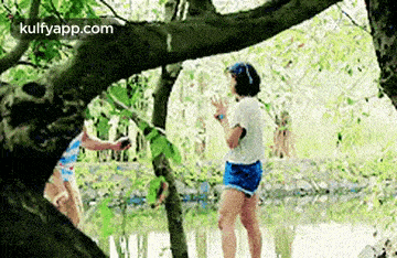 a couple of girls are standing under a tree .