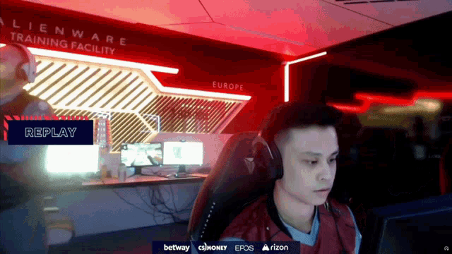 a man wearing headphones is sitting in front of a computer screen with a replay button in the corner