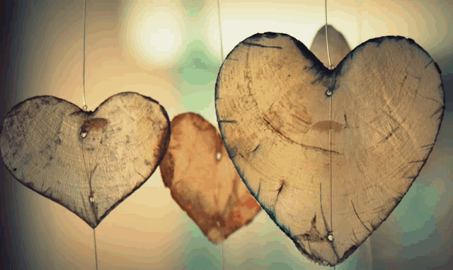 three hearts hanging on a string with a green background