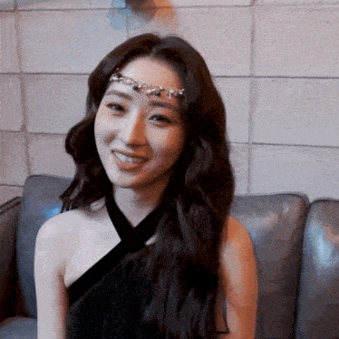 a woman sitting on a couch wearing a headpiece and smiling