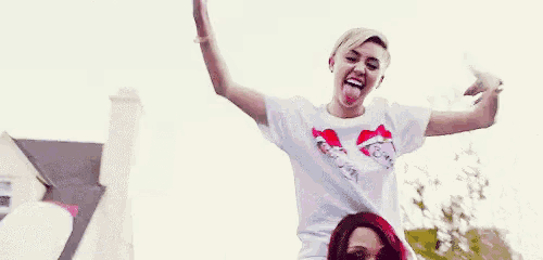 a woman in a white t-shirt is dancing with her arms in the air .