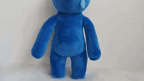 a blue teddy bear is sitting on top of a white surface .