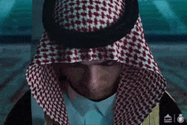 a close up of a man wearing a keffiyeh with arabic writing