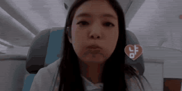 a woman is sitting on an airplane with her mouth open and a heart on the seat .