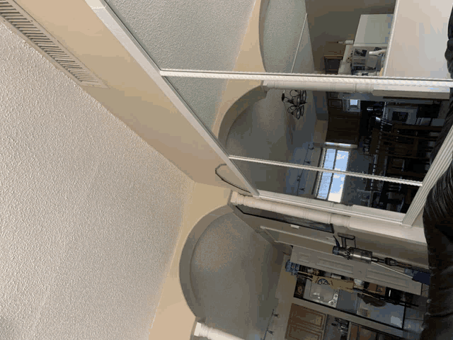 a room with a large mirror on the wall and a reflection of a kitchen