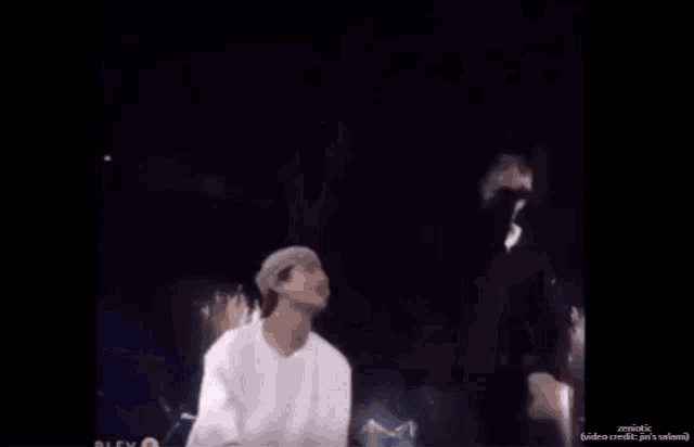 a man in a white shirt and hat says " accidentally hits balls " while standing on a stage