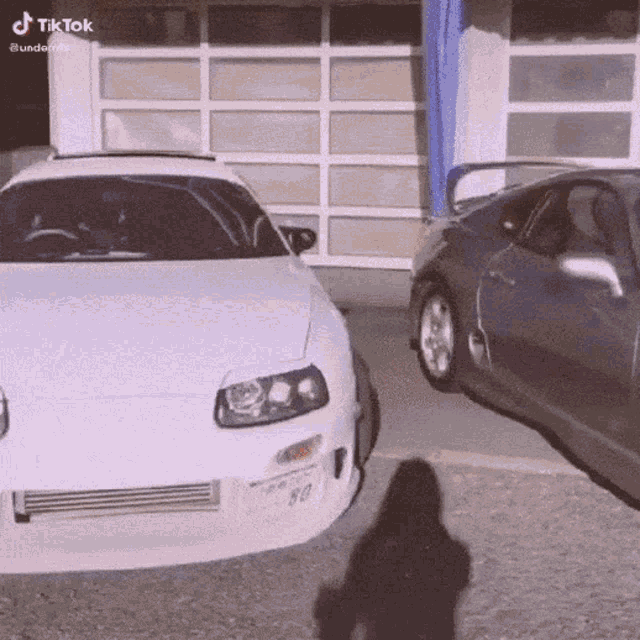a white car with a license plate number 80 is parked next to a black car