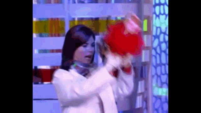 a woman in a white coat is holding a red hat in front of her face .