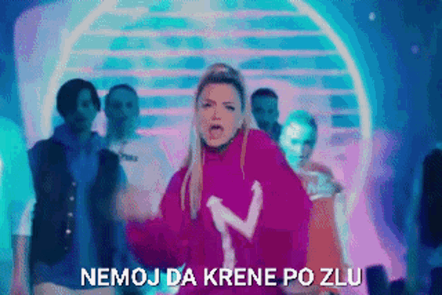 a woman in a pink sweater is dancing in front of a crowd and the words nemoj da krene po zlu are visible