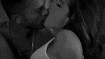 a black and white photo of a man and a woman kissing .