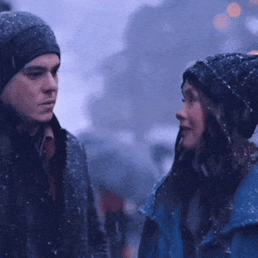 a man and a woman are looking at each other in the rain