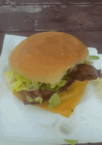 a hamburger with lettuce and cheese on a bun on a napkin