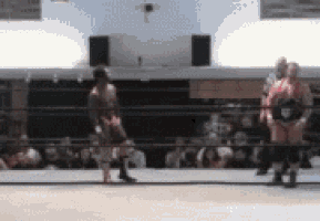 a blurry picture of two wrestlers in a ring with a crowd watching