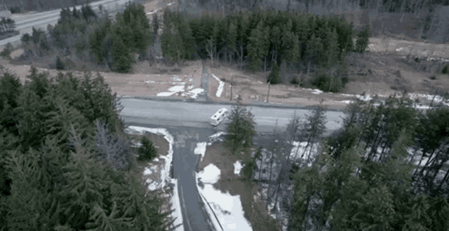 an aerial view of a road surrounded by trees and snow .