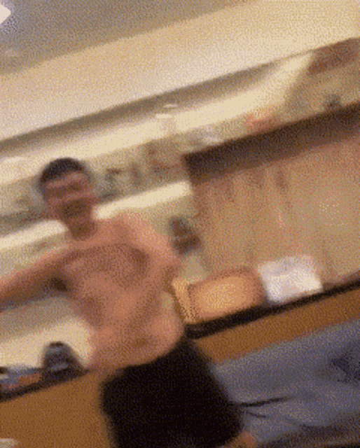 a man without a shirt is standing in front of a mirror in a kitchen
