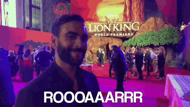 a man is standing on a red carpet in front of a sign that says the lion king