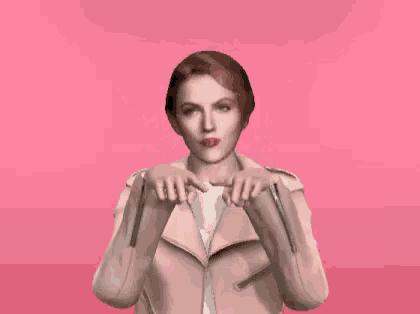 a woman in a pink jacket is making a heart with her hands