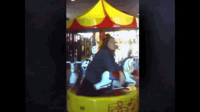 a woman is riding a merry go round in an amusement park .