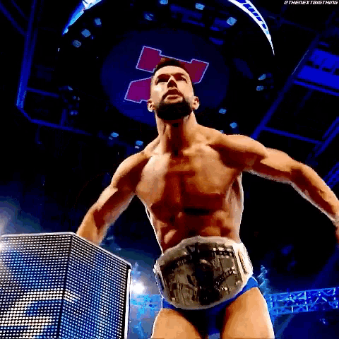a shirtless wrestler is wearing a wrestling belt with the letter n on it .