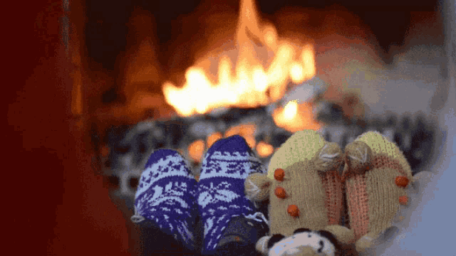 a person wearing knitted socks is sitting in front of a fireplace .