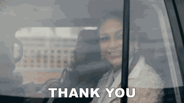 a woman in a car is smiling and the words thank you are behind her